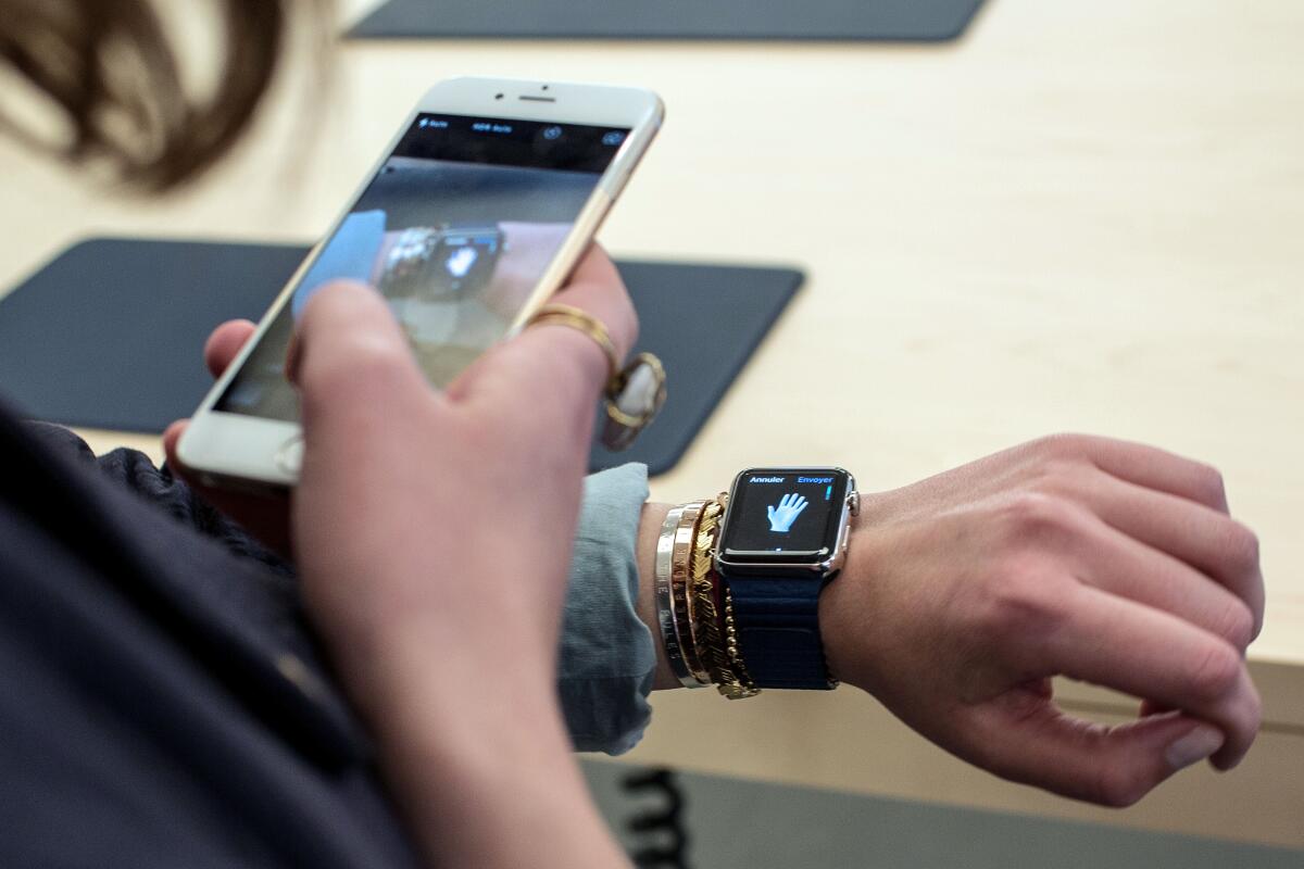 A customer uses an iPhone 6 smartphone to take a photo of a model of the Apple Watch.