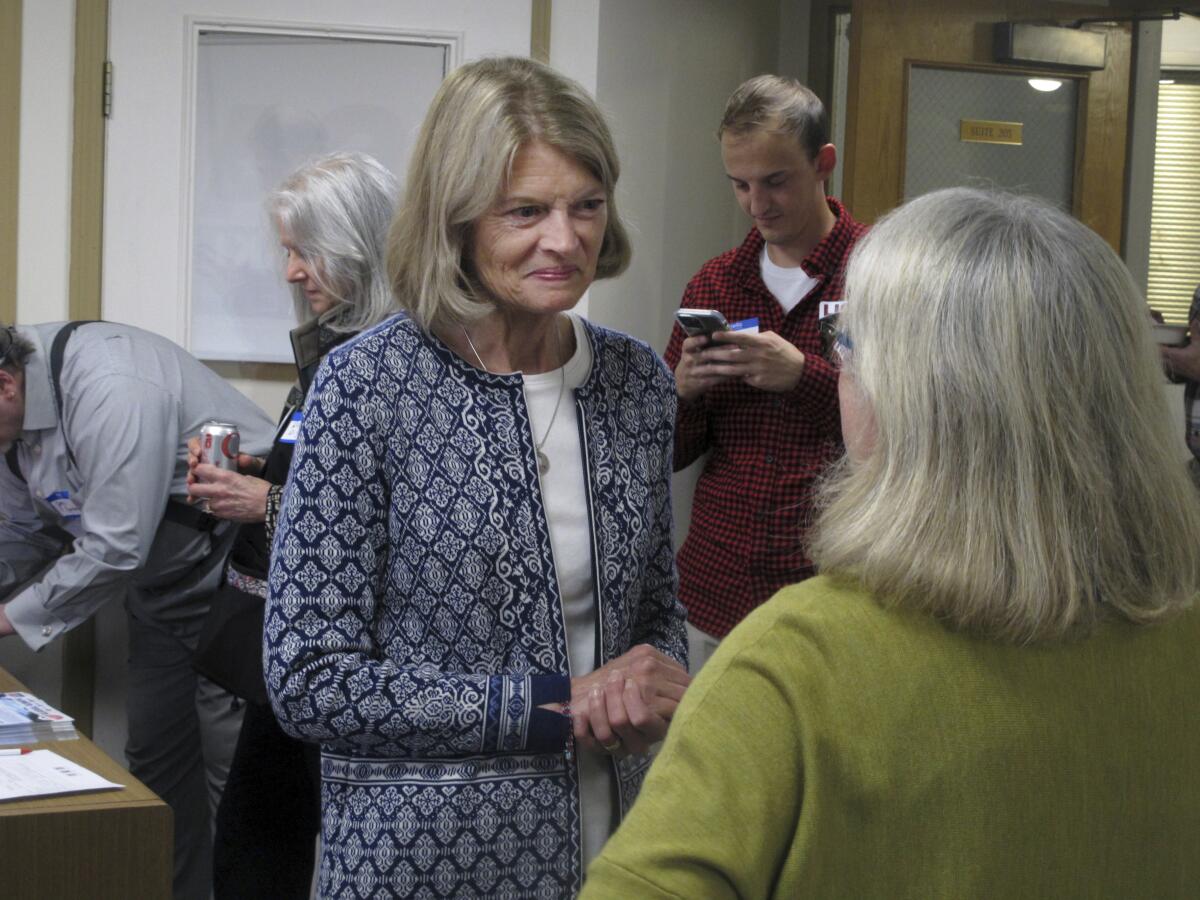 Alaska U.S. Sen. Lisa Murkowski stands in an office with people around her.