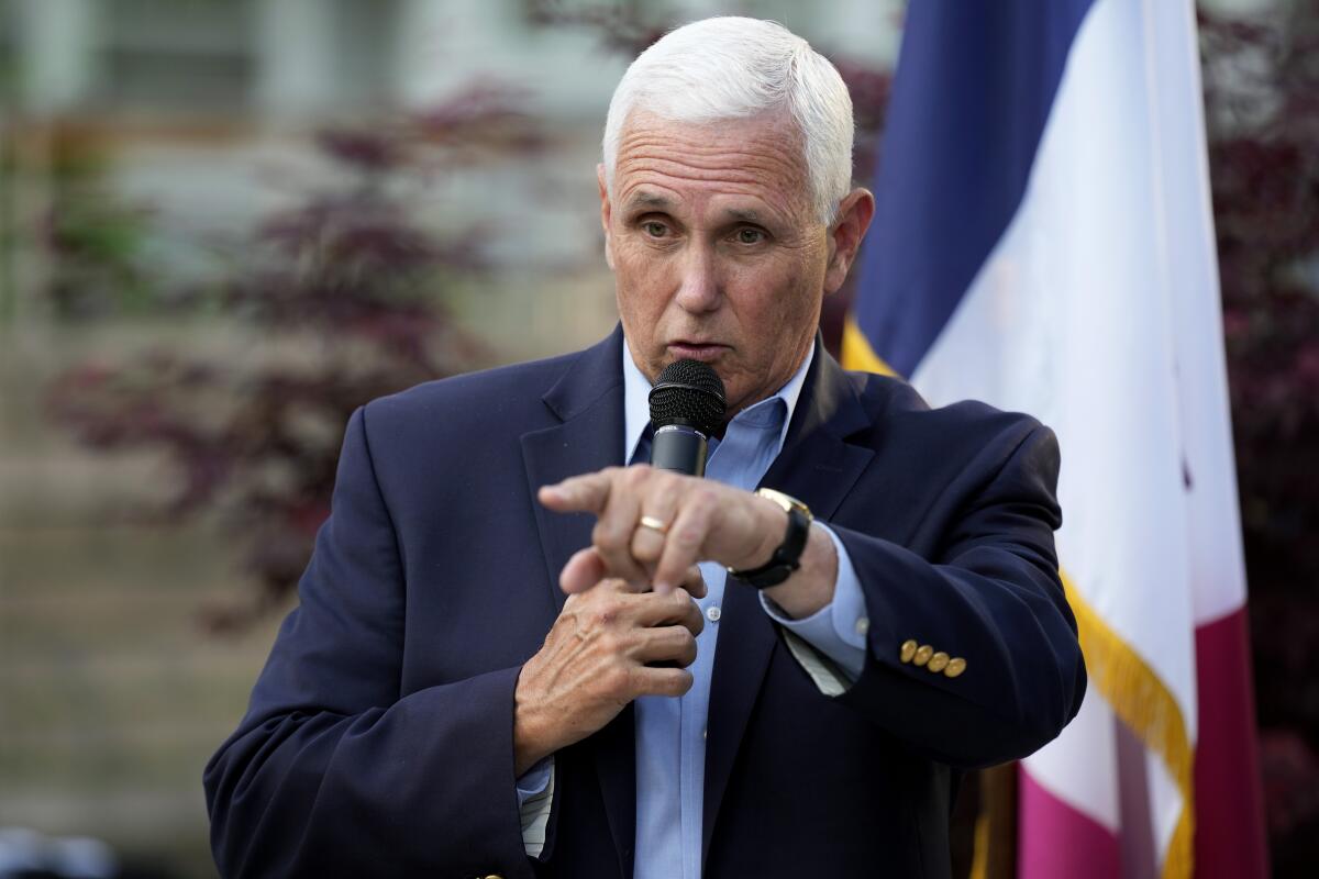 Mike Pence holds a microphone and speaks, pointing in front of him