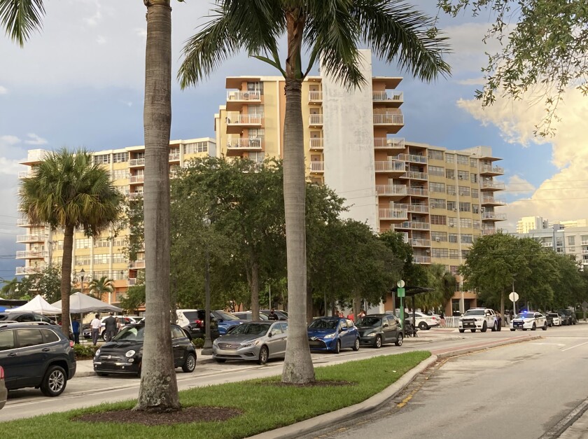 A view of three condo towers on a street with palm trees