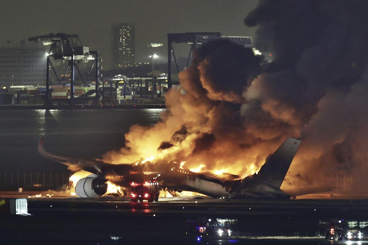 A jetliner in flames on an airport runway at night