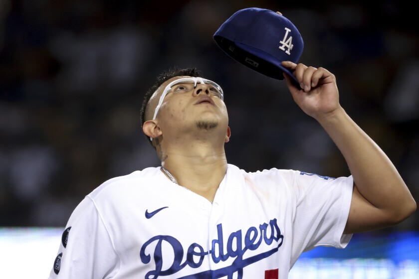     Julio Urías looks up and raises his hat