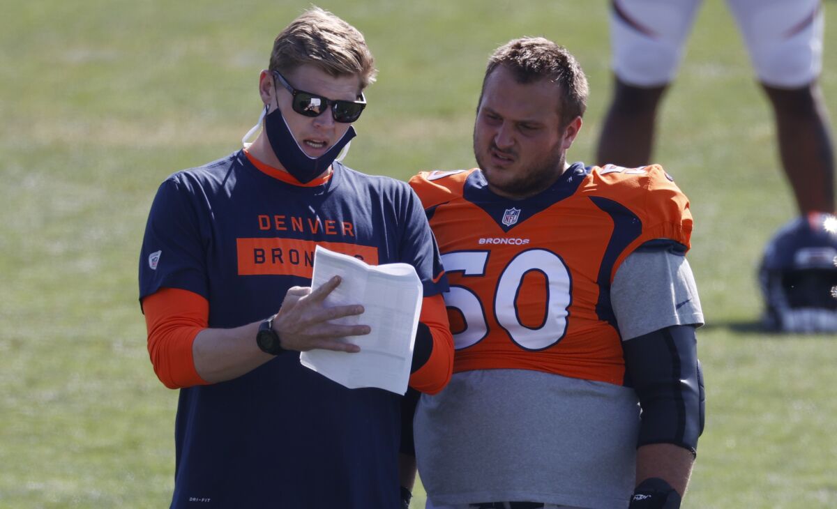 Denver Broncos assistant offensive line coach Chris Kuper, left, confers with center Patrick Morris as he takes part in drills during an NFL football camp practice Monday, Aug. 17, 2020, in Englewood, Colo. (AP Photo/David Zalubowski)