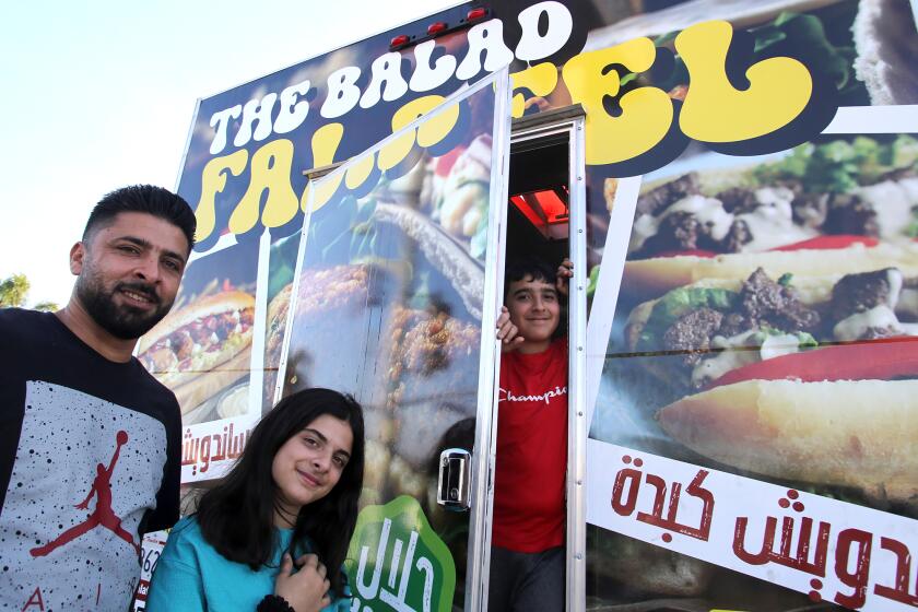 Sanad Morra the owner of Balad Falafel, left, poses with his children Zaina Morra and Mahmoud Morra at his halal cart the Balad Falafel in the Little Arabia District on south Brookhurst Street in Anaheim on Monday, June 10, 2024. The halal cart offers a falafel sandwich, chicken liver sandwich, and ribeye steak sandwich all from family recipes from Palestine. (Photo by James Carbone)