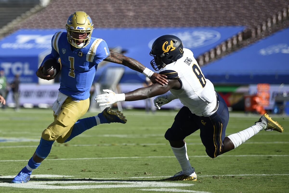 UCLA quarterback Dorian Thompson-Robinson runs the ball while California linebacker Kuony Deng defends.