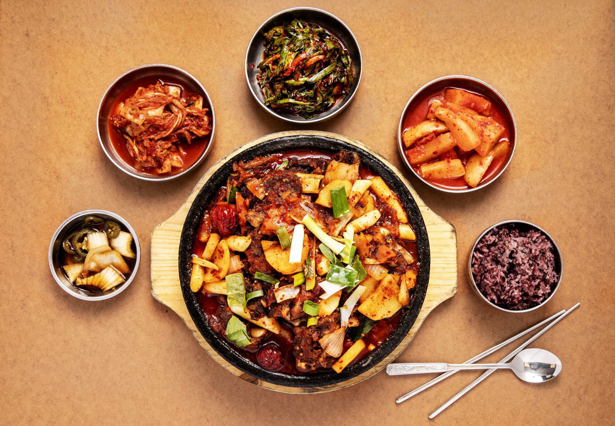 A large round dish of galbi jjim surrounded by five smaller banchan dishes.