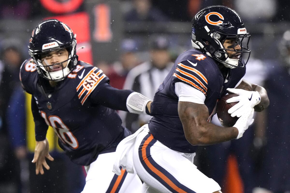 Chicago Bears quarterback Caleb Williams, left, tries to hand off to running back D'Andre Swift.