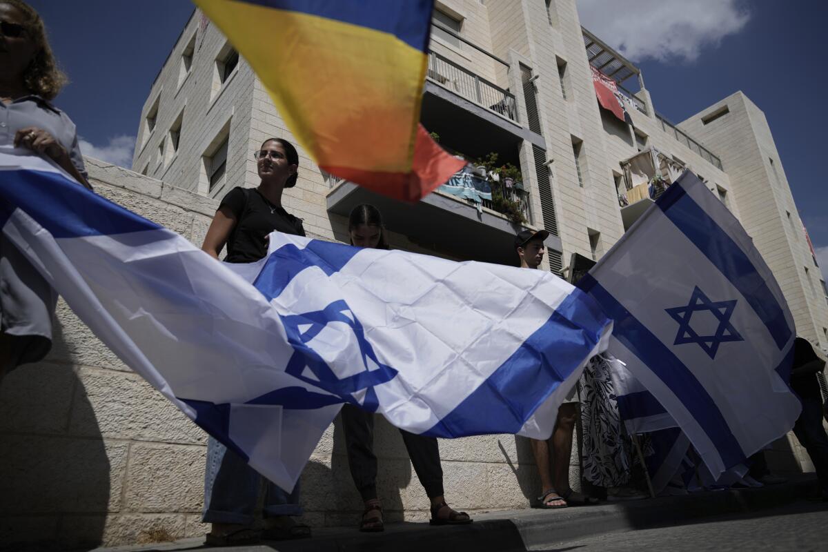 Mourners wave Israeli flags as they accompany the family of Israeli-American hostage Hersh Goldberg-Polin