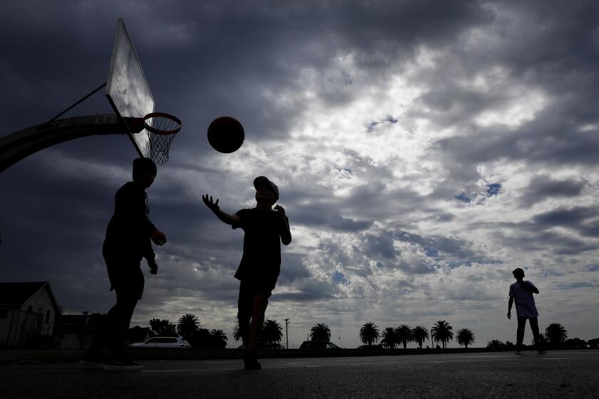 SAN PEDRO-CA-JUNE 22, 2022: Kids play basketball at Angel's Gate Park in San Pedro against cloudy skies. (Christina House / Los Angeles Times)