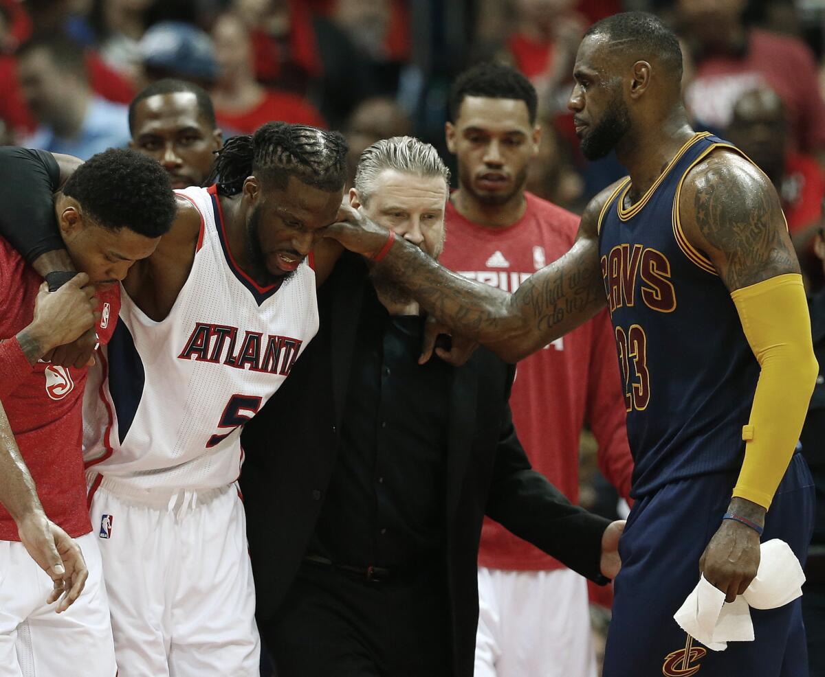 Cavaliers forward LeBron James pats Hawks forward DeMarre Carroll on the shoulder as Carroll is helped off the court after sustaining a knee injury.