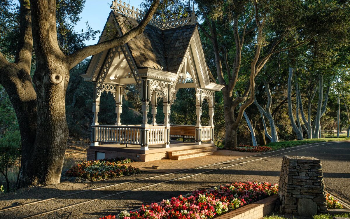 A Victorian-style train station surrounded by trees and flowers on Neverland Ranch 