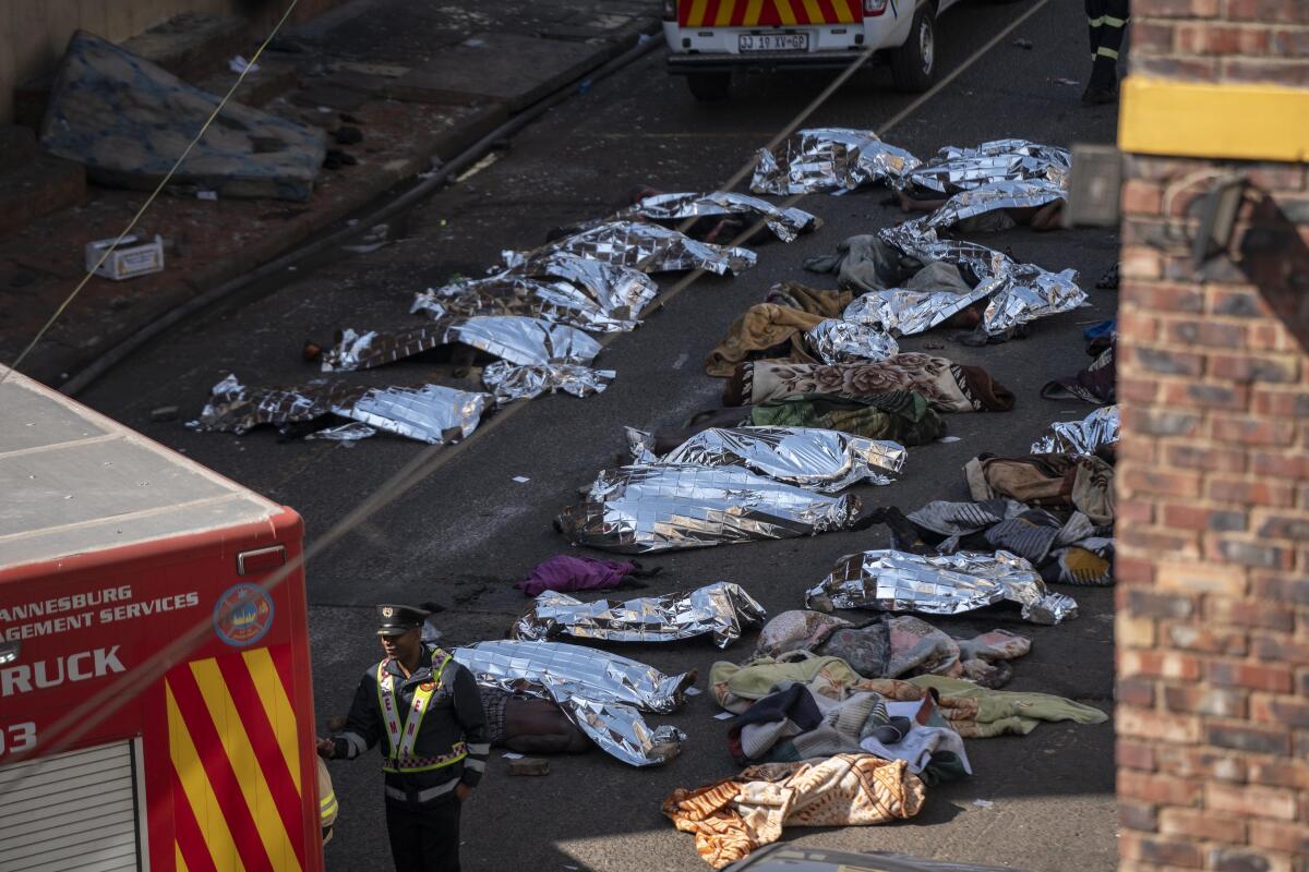  Firefighters and healthcare professionals are deployed at the scene as bodies lie nearby covered in blankets and sheets
