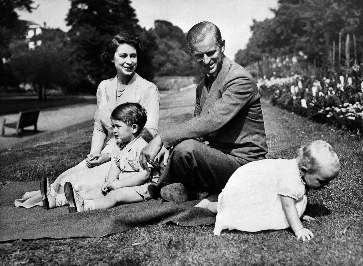 A young British royal family sits on the grass.