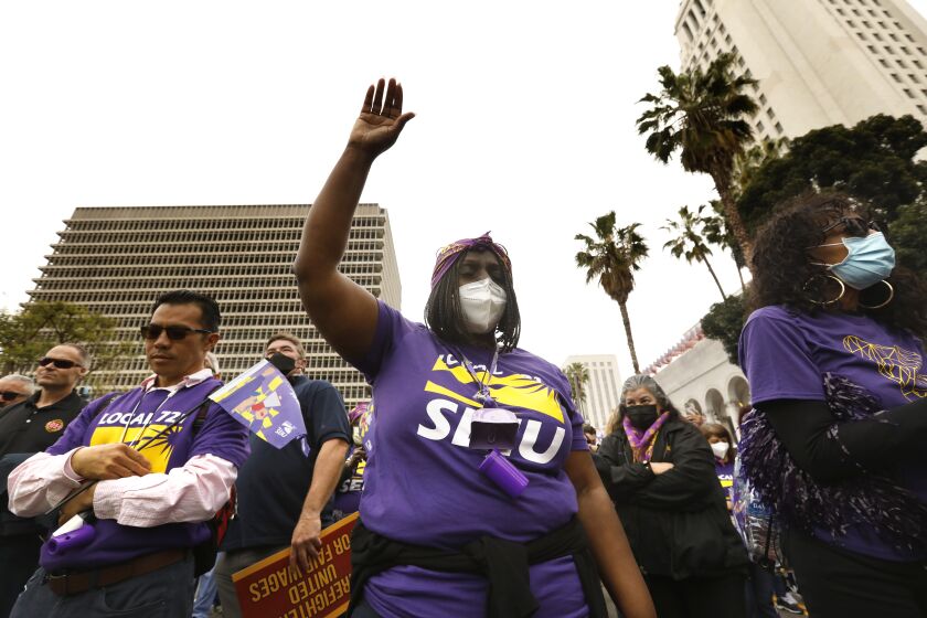 Los Angeles, California-March 31, 2022- -Patty Pitchford, center, takes part in a moment of silence for those people victims of COVID during a rally of the SEIU Local 721 on March 31, 2022. About 5,000 workers from the SEIU Local 721 rally at the Kenneth Hall of Administration Building in downtown Los Angeles. SEIU stands for Service Employees International Union. A six-month long short-term contract between SEIU Local 720 and Los Angeles County is set to expire Thursday at midnight. After that point, SEIU members will discuss options, including a potential strike, which will be needed to be voted on by the roughly 55,000 members. The employees work all over the county and represent departments such as Los Angeles County-USC Medical Center, Los Angeles County Department of Public Social Services, Los Angeles County Department of Children and Family Services. (Carolyn Cole / Los Angeles Times)