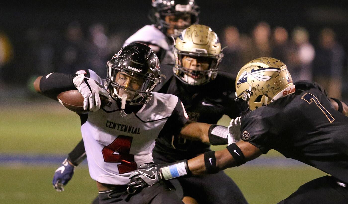 Centennial's Miles Reed tries to escape the grasp of St. John Bosco's Stephan Blaylock during their Southern Section Division 1 semifinal football game at Cerritos College on Friday night.