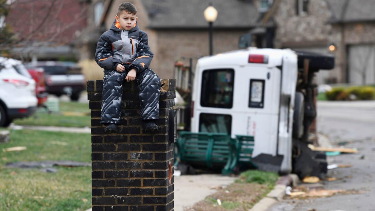Gio Rodriguez, 8, sits outside his home as his parents clean up debris on Feb. 25, 2018, after a storm hit in the Farmington subdivision in Clarksville, Tenn.