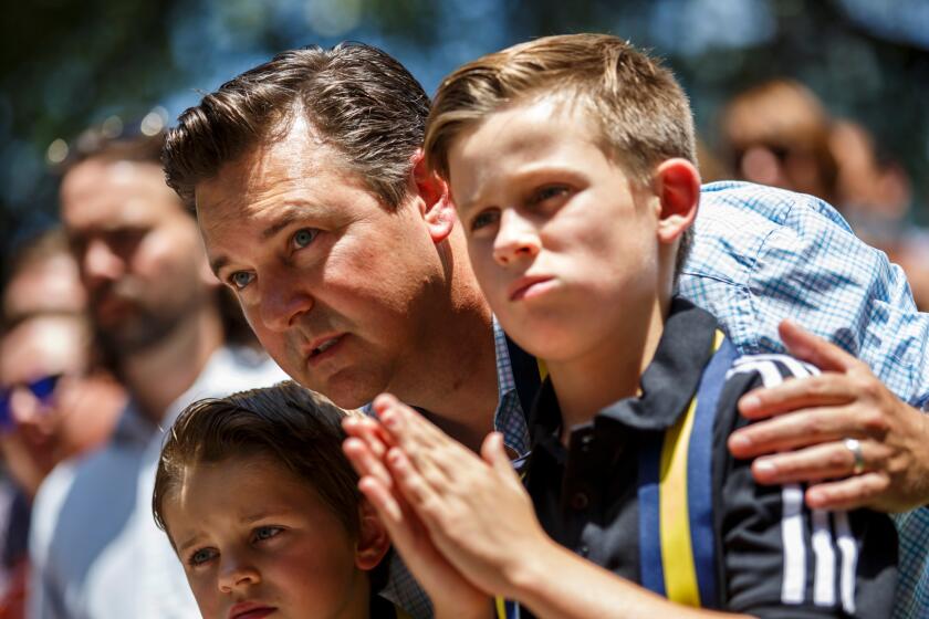 Ethan Boothe, center, talks to his sons Greyson Boothe, 8, left, and Austin Boothe, 10, right, attends an interfaith prayer service for the victims of the police shooting.