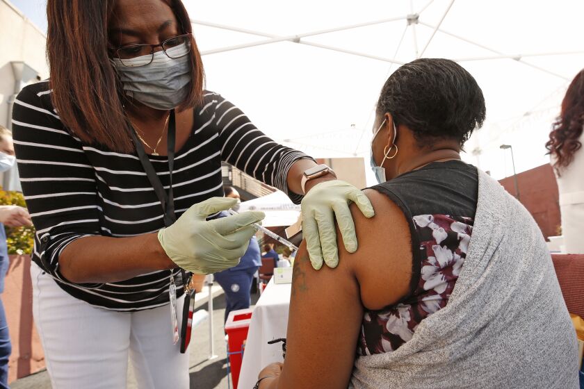 LOS ANGELES, CA - APRIL 20: Hadizatou Toure, 35, receives the Pfizer Covid-19 vaccination from registered nurse Janice Taylor at a new, walk-up mobile COVID-19 clinic launched today to provide the Pfizer COVID-19 vaccine to underserved communities in Los Angeles. The walk-up clinic was presented by Councilmember Mark Ridley-Thomas in partnership with CHA Hollywood Presbyterian Medical Center (CHA HPMC) and the Southern California Eye Institute (SCEI). The Mobile Vaccine Clinic at 1819 S. Western Avenue will be open every Tuesday starting April 20 through May 25 providing free vaccines to community members who are eligible per LA County Department of Public Health (LAC DPH) vaccine distribution guidelines as they partnered with Charles R. Drew University of Medicine and Science to provide student volunteers for on-site registration allowing for walk-up appointments for community members and further ensuring vaccine access in our hardest-hit communities. Los Angeles on Tuesday, April 20, 2021 in Los Angeles, CA. (Al Seib / Los Angeles Times).