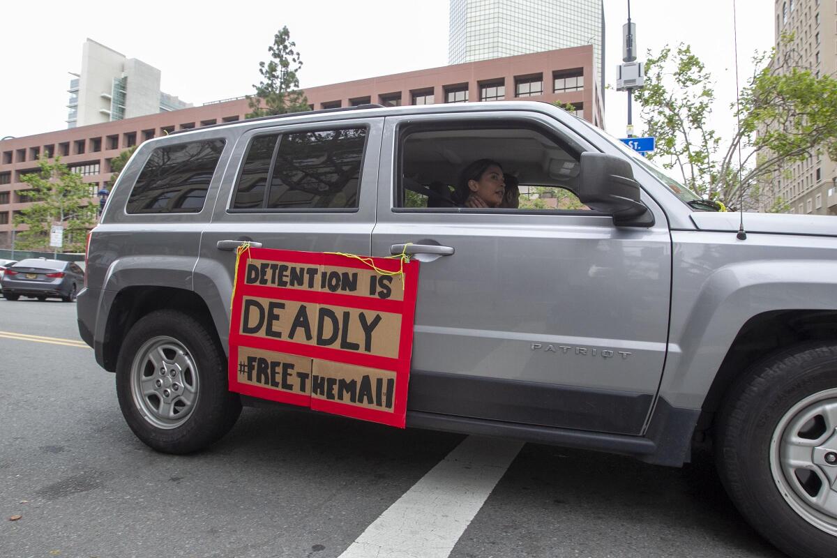 A sign on an SUV reads, "Detention is deadly, free them all." 