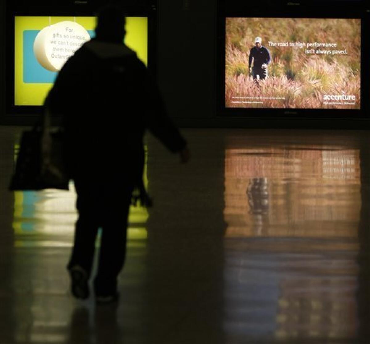 A passenger walks near an ad for consulting firm Accenture featuring Tiger Woods at Dulles International Airport in Chantilly, Va. Monday, Dec. 14, 2009. Accenture, which pinned its entire identity on the golfer, severed its ties with Woods on Sunday, days after he announced an indefinite leave from golf to work on his marriage after allegations of infidelity surfaced in recent weeks. (AP Photo/Luis M. Alvarez)