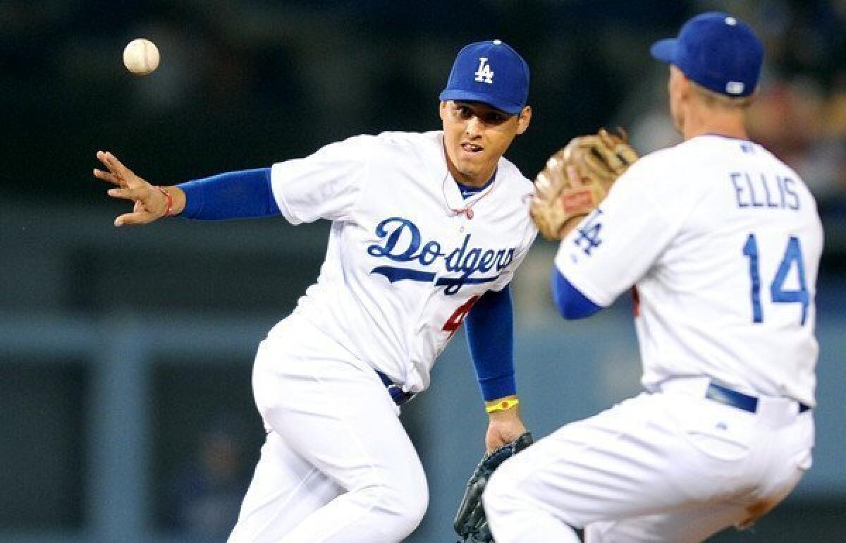 Dodgers shortstop Luis Cruz tosses the ball to second baseman Mark Ellis to begin a double play against the Giants.