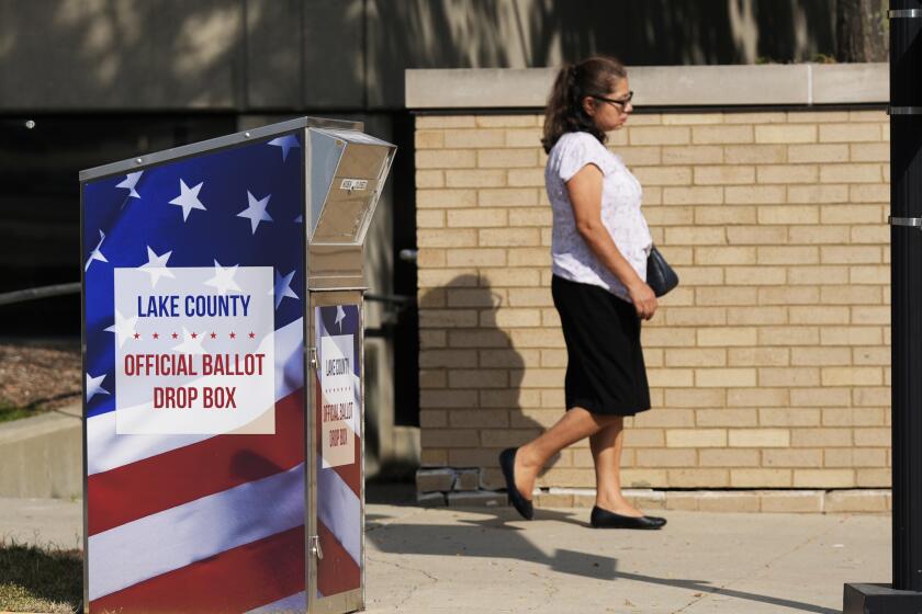 Una persona pasa por delante de un buzón de votos para el condado de Lake en el centro de Waukegan, Illinois, el lunes 16 de septiembre de 2024. (AP Foto/Nam Y. Huh)