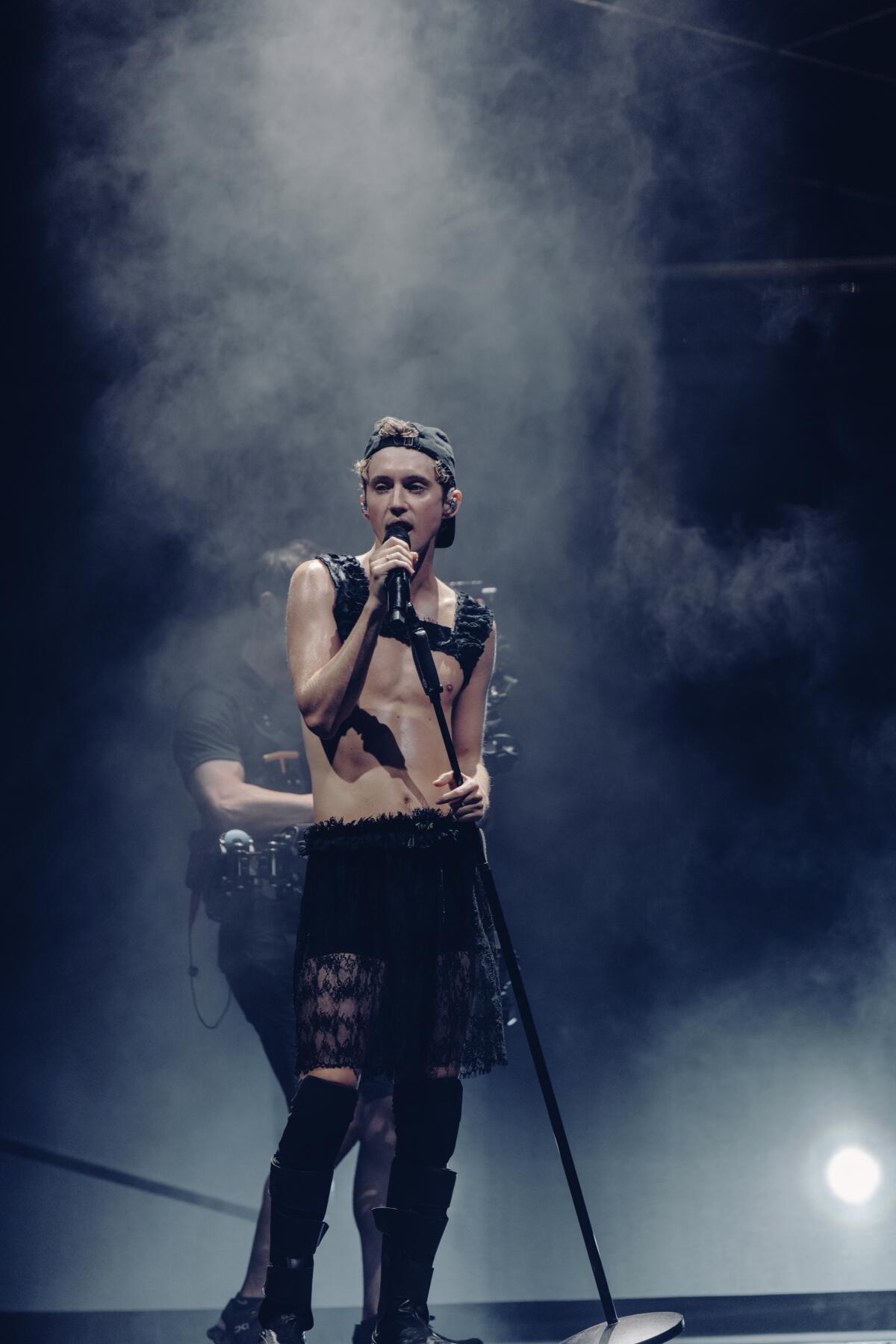 Troye Sivan performs in a smoky atmosphere.