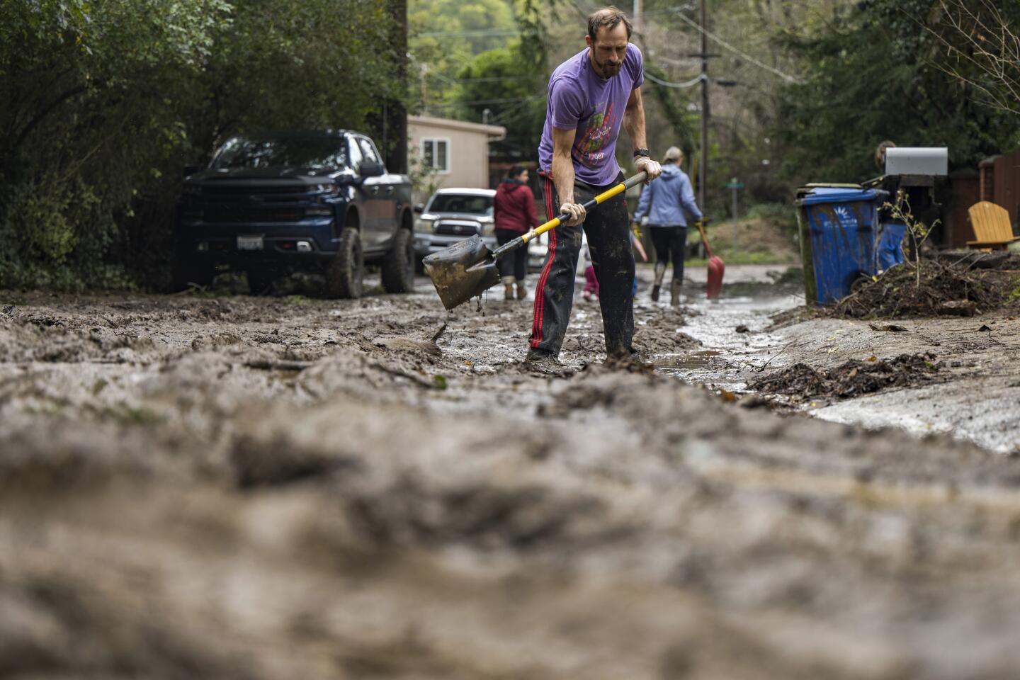A man shovels mud from a friend's driveway