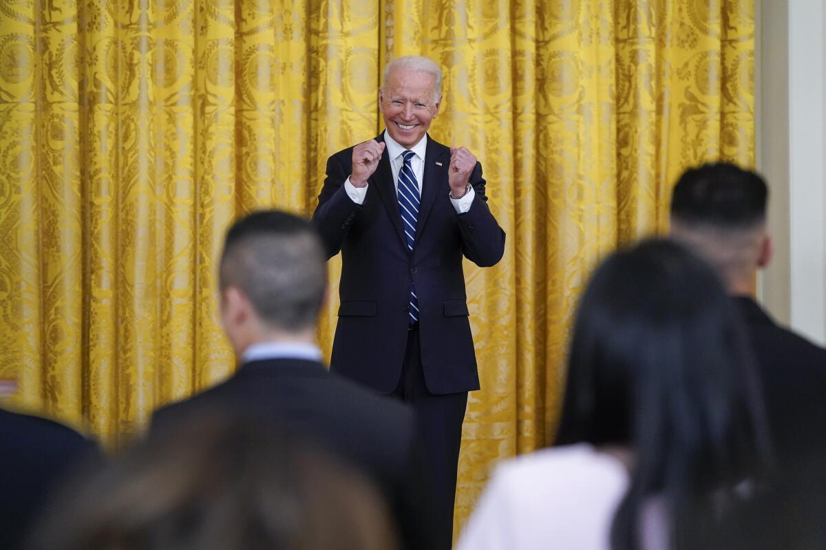 President Biden has a big smile as he stands on the stage in the White House's East Room