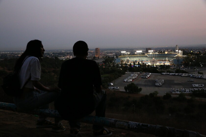 Samantha Alvarez and Benjamin Hernandez watch from a distance as the Dodgers play the Milwaukee Brewers.