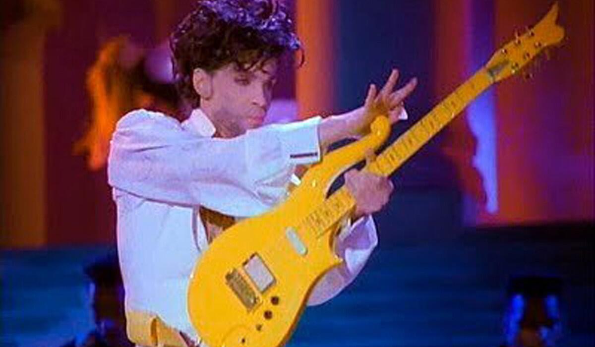 Prince plays his Yellow Cloud electric guitar at a concert.