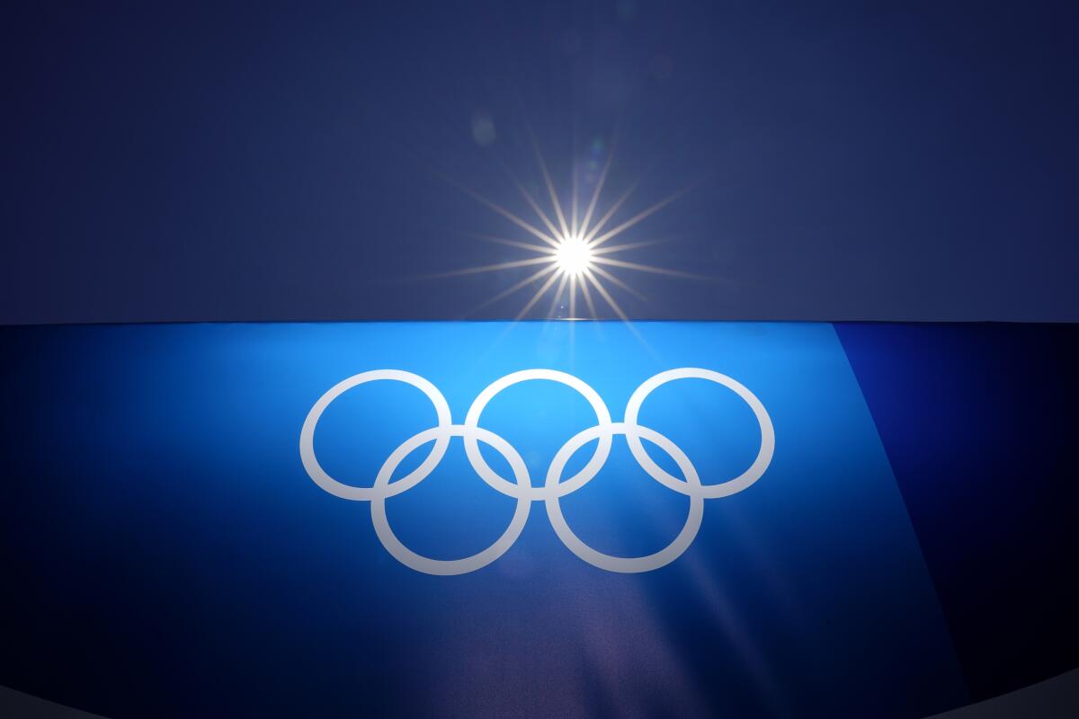 The sun shines above an image of the Olympic rings at Yokohama Baseball Stadium.
