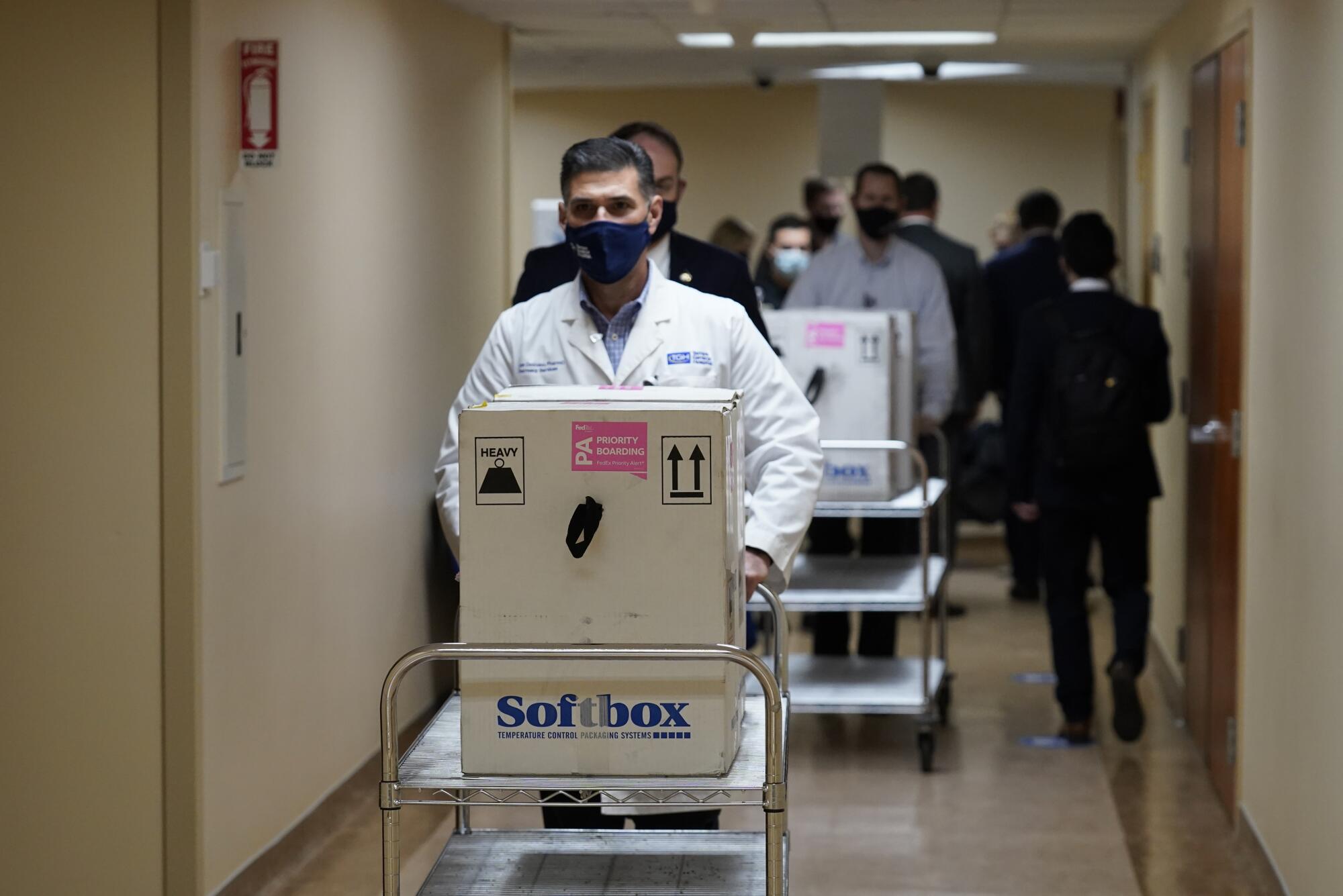 Medical workers wheel boxes on carts 