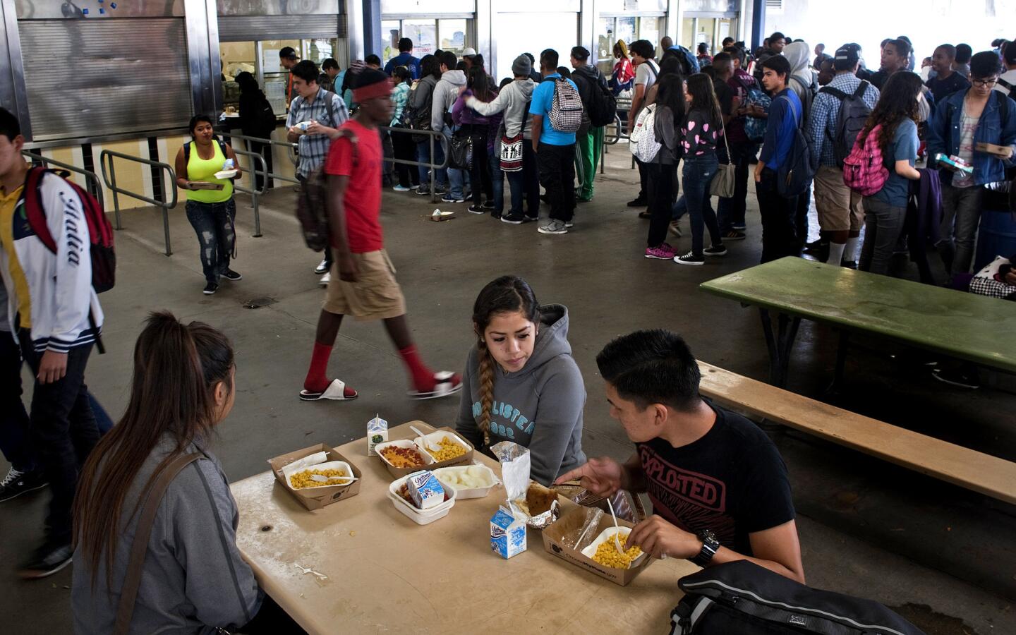 Mele Vehikite, 16, left, Ellie Gutierrez, 17, and Antonio Ramos, 18, eat lunch at Washington Preparatory High School in L.A. The school is required to serve three items, including a fruit and a vegetable, even if students do not want them.