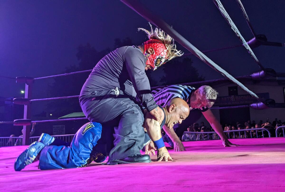 A person is on the back of another in a wrestling ring.