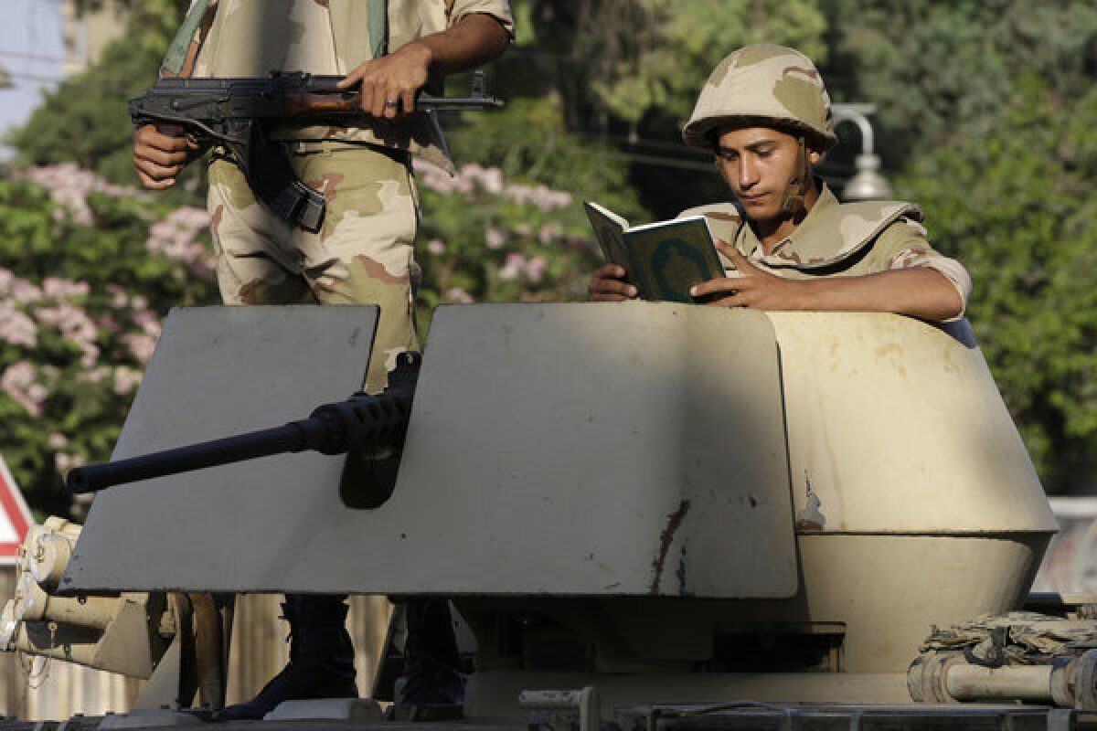 An Egyptian soldier reads Islam's holy book, the Koran, in his armored personnel carrier near the presidential palace in Cairo.
