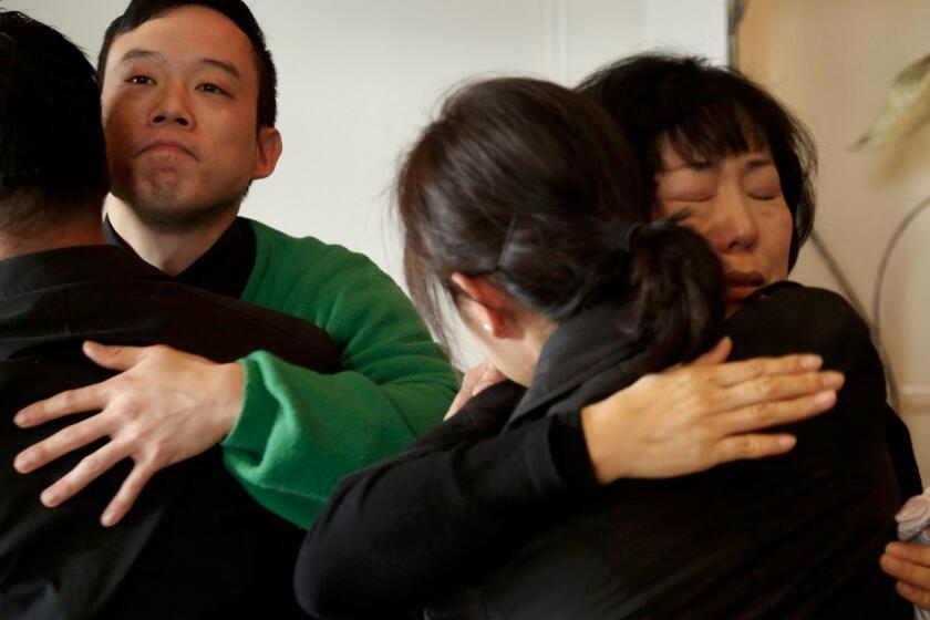 Hoona Jo, second from left, brother of Ara Jo, and their mother Yoo Sook Jo are consoled by mourners at Ara Jo's funeral in Koreatown.