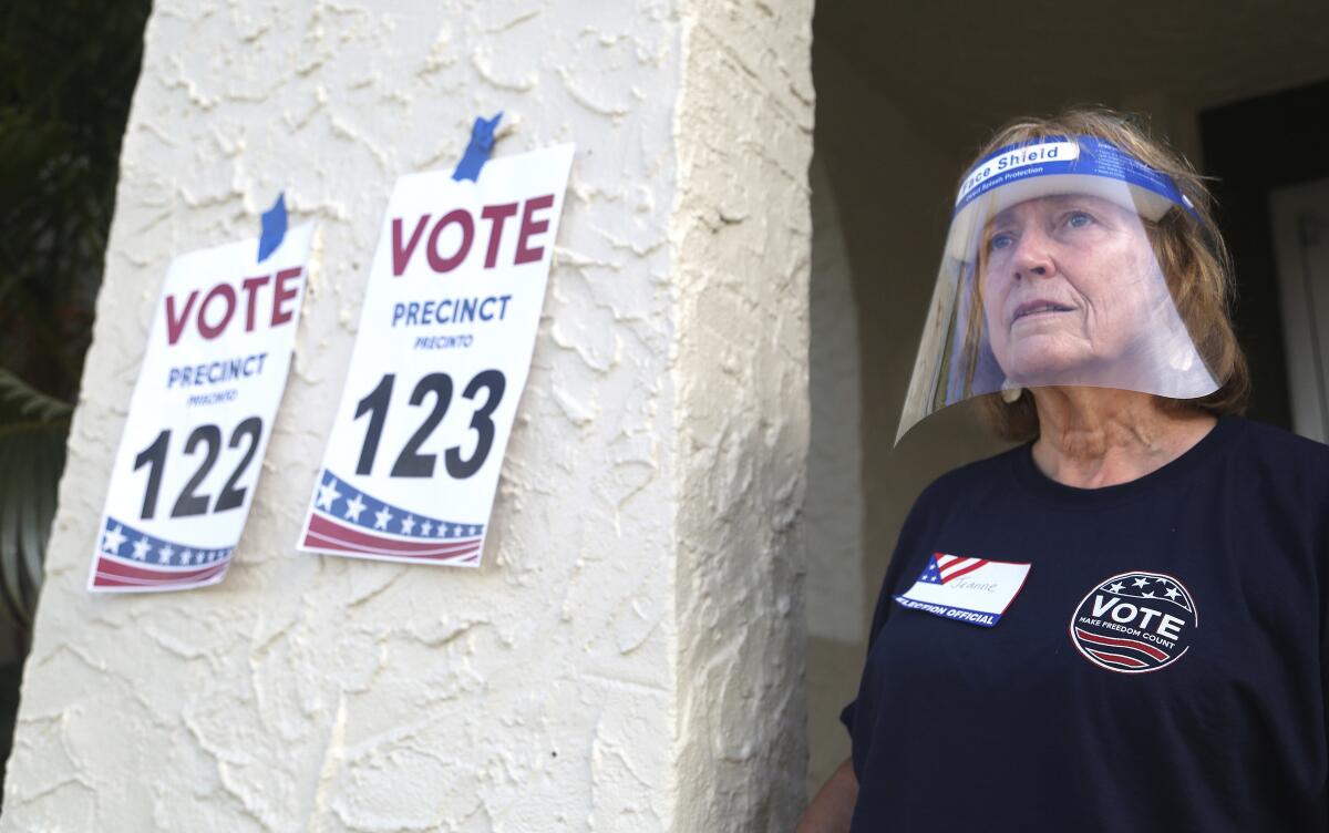 Pinellas County poll worker Jeanne Coffey wears a protective shield outside a polling place in St. Petersburg, Fla.