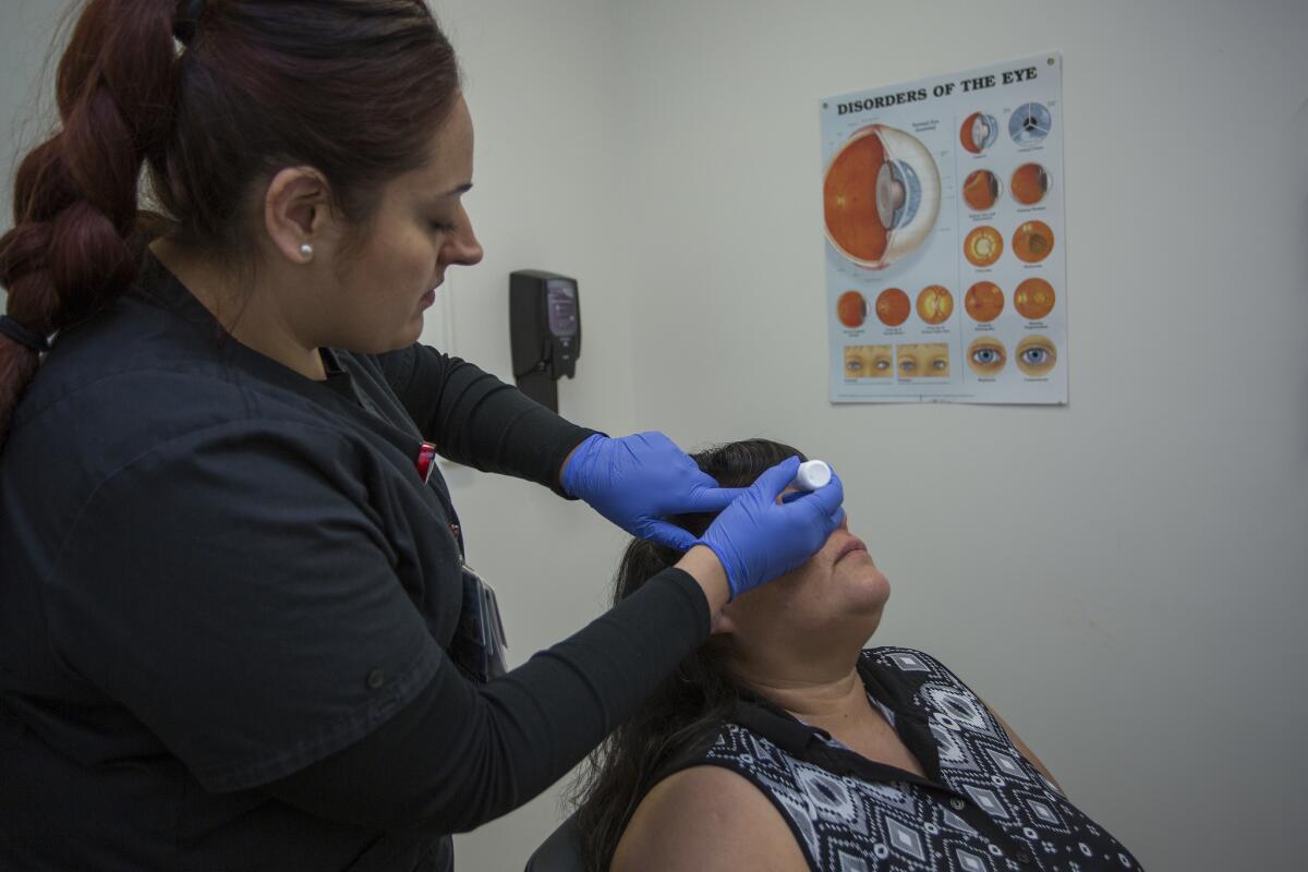 Silvia Fletes gives Rosa Guzman eyedrops before photographing her retinas to screen for diabetic retinopathy.