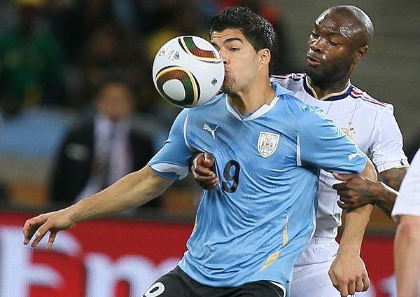 Uruguay striker Luis Suarez, left, is hit by the ball in front of France defender William Gallas during a Group A World Cup match on Friday at Green Point Stadium in Cape Town.