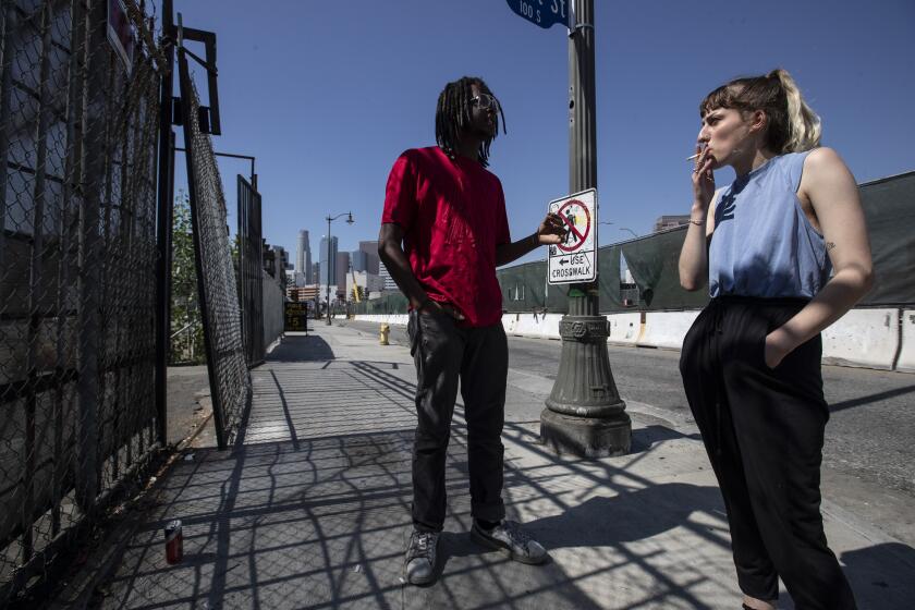 LOS ANGELES, CALIF. -- FRIDAY, OCTOBER 4, 2019: Loxk Calhoun, left, (real first name DaShawn) and Bri Meilbeck, right, share a cigarette in downtown Los Angeles, Calif., on Oct. 4, 2019. (Brian van der Brug / Los Angeles Times)