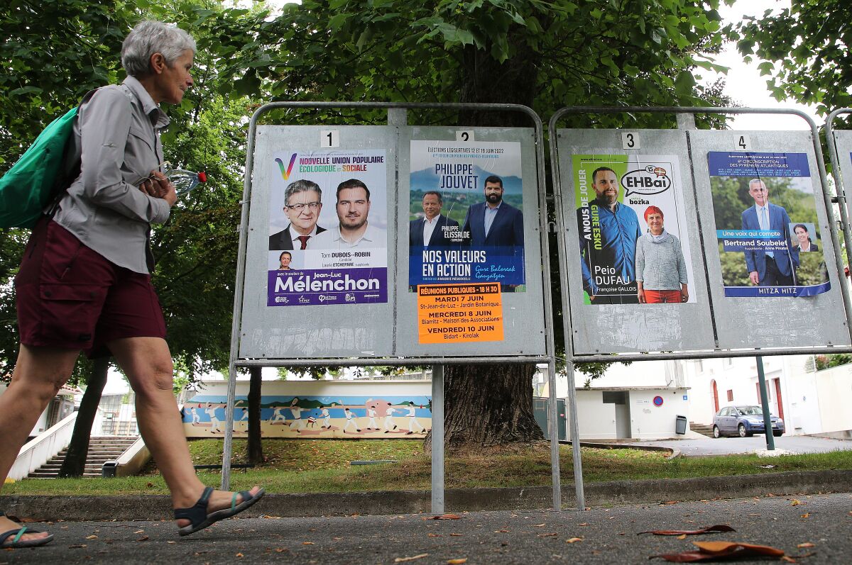 A woman walks past electoral posters of the upcoming parliamentary elections in Saint Jean de Luz, southwestern France, Wednesday June 8, 2022. The legislative elections will take place on June 12 and 19, 2022. (AP Photo/Bob Edme)