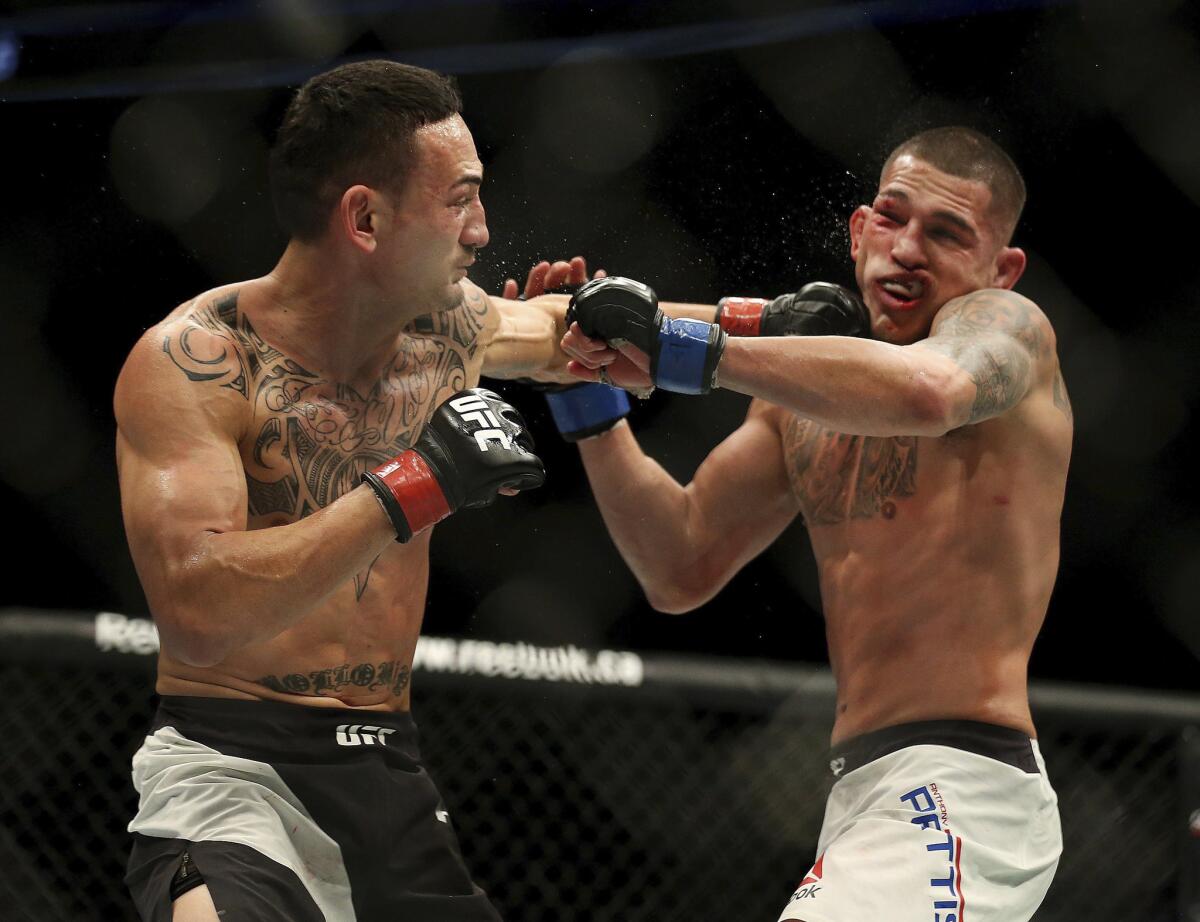 Max Holloway, left, punches Anthony Pettis during their interim featherweight title bout at UFC 206. To see more images from the fight card, click on the photo above.