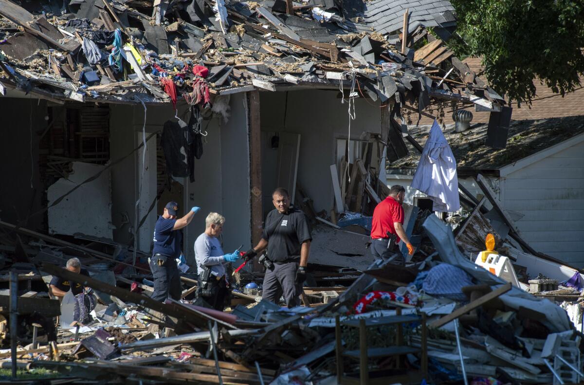 Emergency personnel search the debris, Thursday, Aug. 11, 2022, in Evansville, Ind., as authorities work to determine the cause of a house explosion that killed three people and left another person hospitalized. The explosion the day before damaged 39 homes. (MaCabe Brown/Evansville Courier & Press via AP)