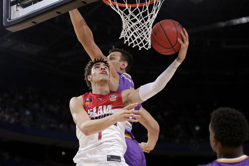 LaMelo Ball of the Illawarra Hawks, left, lays up around Andrew Bogut of the Sydney Kings.