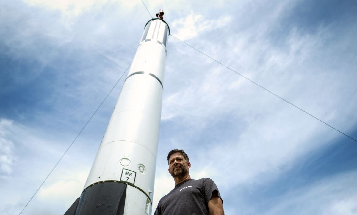 A man stands next to a model rocket.