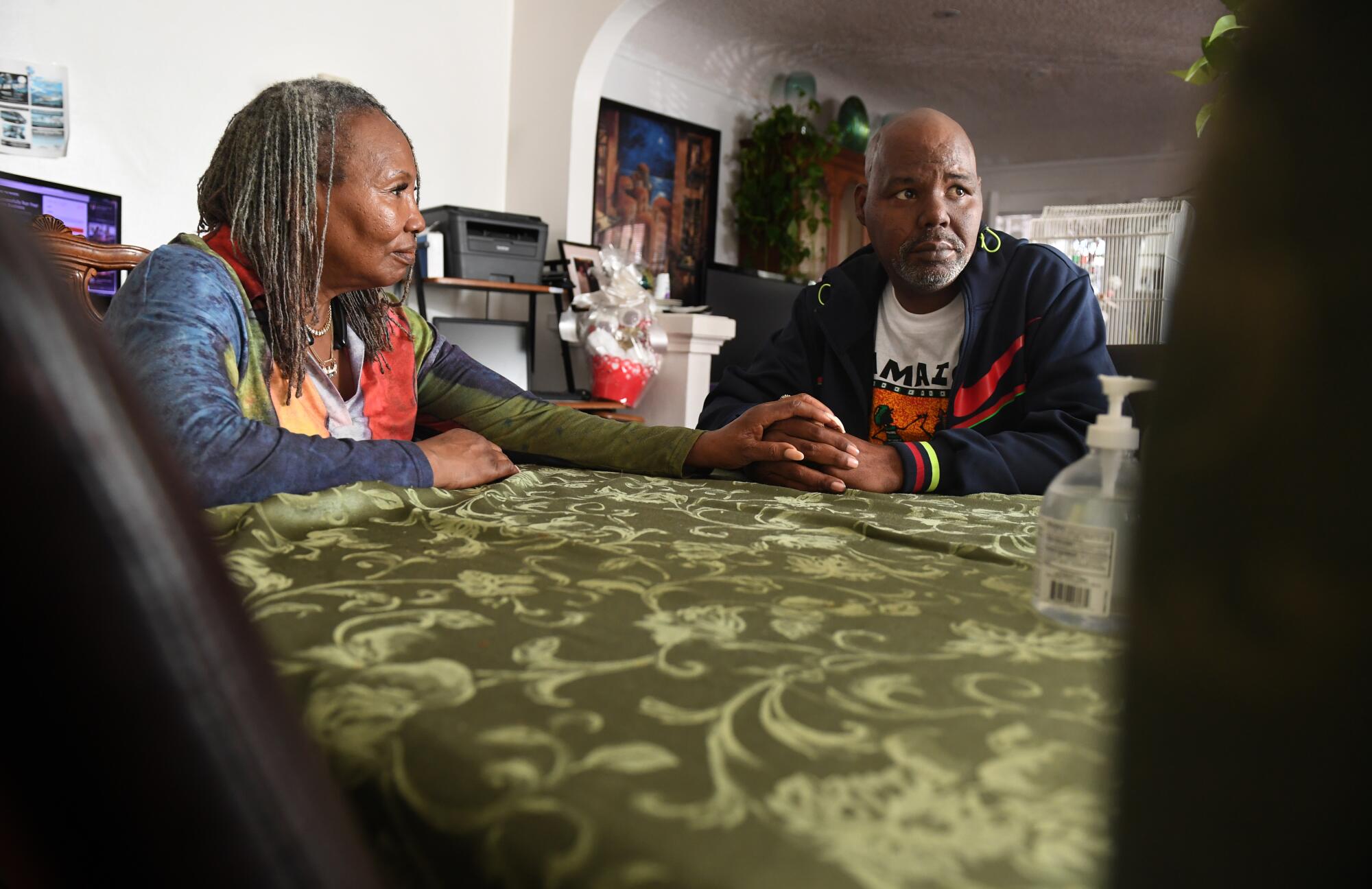 A woman and her adult son sit at a table in their Los Angeles home