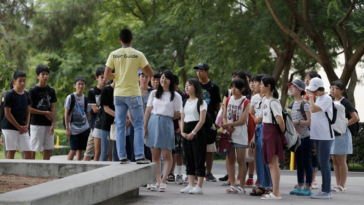 A tour guide leads a group of students around the UC Irvine campus.