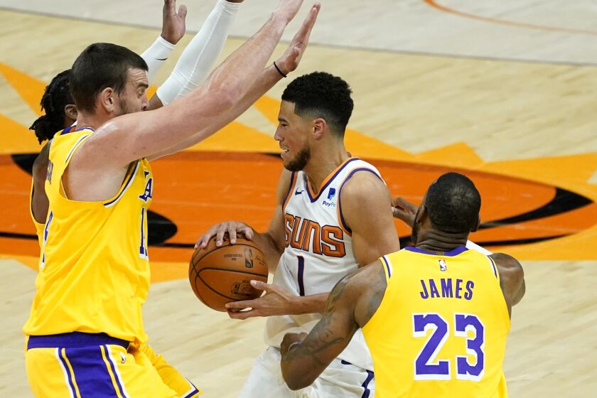 Phoenix Suns guard Devin Booker (1) is pressured by Los Angeles Lakers forward LeBron James (23) and Marc Gasol during the second half of a preseason basketball game, Friday, Dec. 18, 2020, in Phoenix, Ariz. (AP Photo/Matt York)