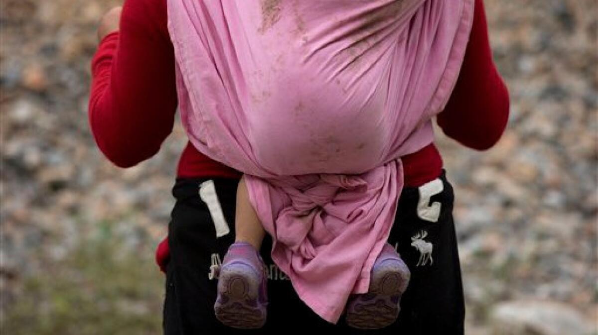 A Central American migrant carrying a small child waits alongside a stuck northbound freight train, outside Reforma de Pineda, Chiapas state, Mexico.